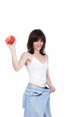 The beautiful girl in jeans of the big size holds a red apple in a hand