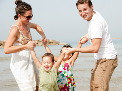 Young couple embracing and enjoying with two young children in beach