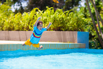 Kids jump into swimming pool. Summer water fun.