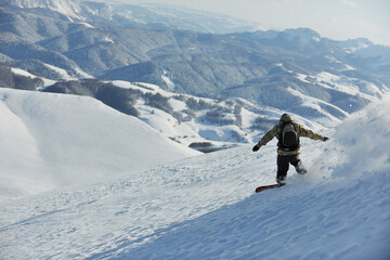 freestyle snowboarder jump and ride free style  at sunny winter day on mountain