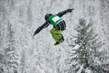 young boys jumping in air ind showing trick with snowboard at winter season