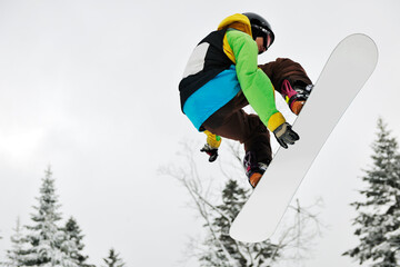 Fototapeta na wymiar young boys jumping in air ind showing trick with snowboard at winter season
