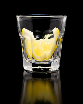 tequila shot on bar with lemon slice on black background