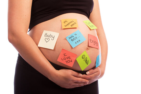Young pregnant Caucasian woman with notes stuck on her belly