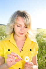 Young Sexy blonde on background of green meadow with daisywheel