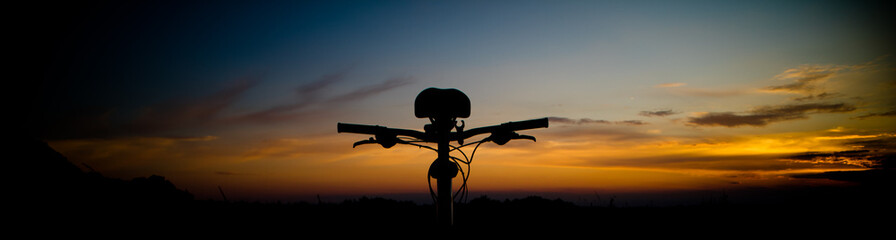 Beautiful landscape image with Bicycle at sunrise. Composition with bicycle and landscape. Bicycle handlebars on the background of the sky.