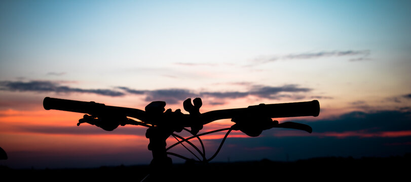 Beautiful landscape image with Bicycle at sunrise. Composition with bicycle and landscape. Bicycle handlebars on the background of the sky.