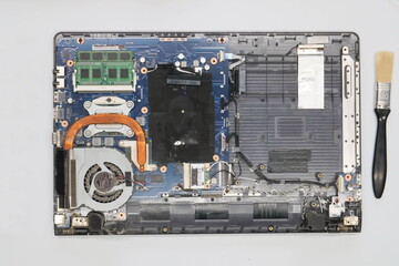 Disassembled laptop on a white background. Isolated. Broken dusty computer in a service workshop for cleaning and repair. Computer motherboard, chips, fan, wires, connectors, cooling system. Close-up