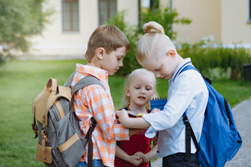 children walking from school with backpacks on sunny day. Begining of academic year. Boys by school...