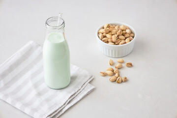 Homemade vegetable milk from pistachio nuts. Pistachio milk in a bottle on a gray concrete table. Ideal for vegans. place for text