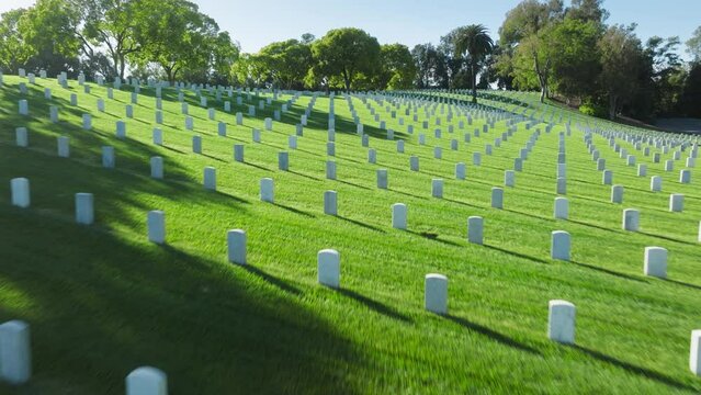 Aerial Los Angeles National Cemetery California USA. Drone flying above scenic green field with straight rows white grave plates on summer day. National cemetery where buried all members armed forces
