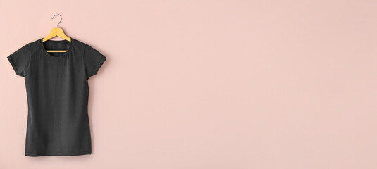Hanger with black woman's t-shirt on pink background with space for text