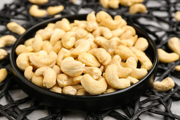 Plate with tasty cashew nuts on grunge background