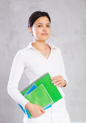 Student girl with several notebooks for writing poses in studio.Specialized education,distance learning abroad,continuing education