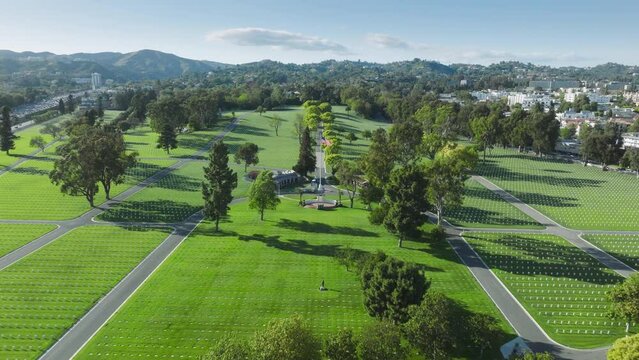 Aerial Los Angeles National Cemetery California USA. Drone flying above scenic green field with straight rows white grave plates on summer day. National cemetery where buried all members armed forces