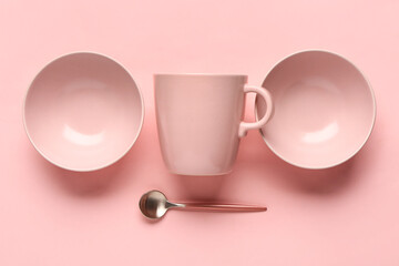 Composition with clean bowls, cup and spoon on pink background