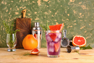 Glass of purple gin and tonic with grapefruits on wooden table