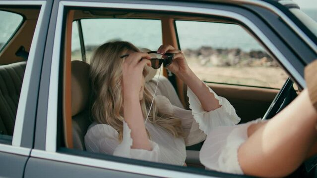 Pretty woman passenger relaxing in retro car putting legs at open window closeup