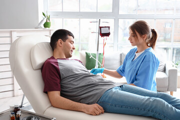 Female nurse taking blood from young donor in clinic