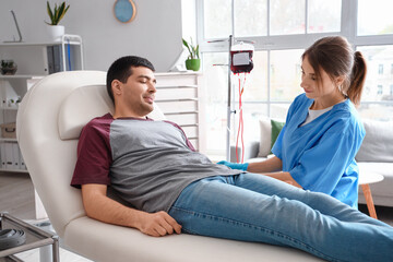 Female nurse taking blood from young donor in clinic