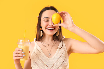 Young woman with glass of smoothie and lemon on yellow background, closeup