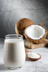 Glass of coconut milk with pieces of coconut on the table.