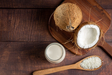 Glass of coconut milk with pieces of coconut on the table.