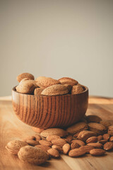 Bowl of shelled almonds in wooden bowl and peeled almonds on wooden board