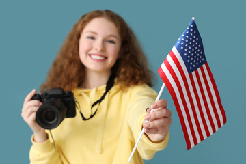 Young woman with USA flag and photo camera on blue background, closeup