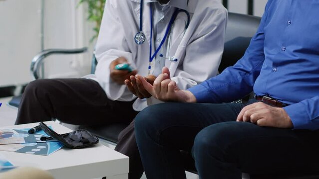 Physician doing insulin level measurement with medical instrument to help asian patient with diabetes during checkup visit appointment in hospital waiting room. Medicine support service