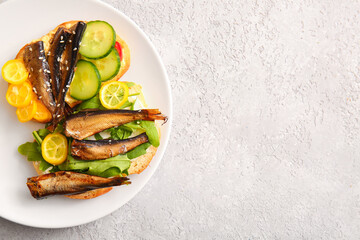 Plate of tasty sandwiches with canned smoked sprats on grey background