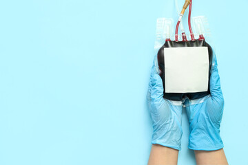 Female doctor with blood pack on blue background. World Donor Day
