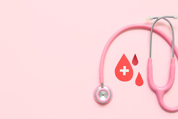 Paper blood drops with stethoscope on pink background. World Donor Day