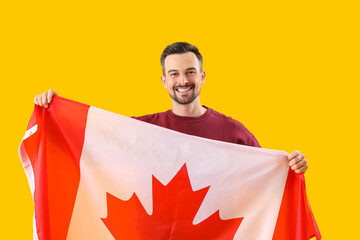 Handsome man with flag of Canada on yellow background
