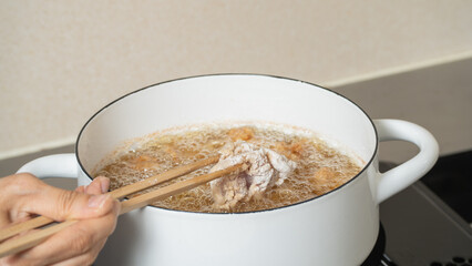 鶏の唐揚げ・調理シーン　味付けした鶏もも肉を油へ入れる