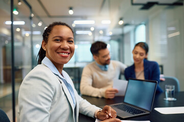 Happy black financial consultant on meeting with her clients looking at camera.