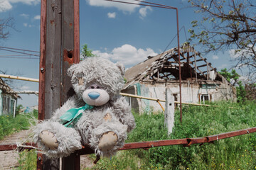 Countryside. A toy (teddy bear) in front of a house destroyed by artillery shelling. War in Ukraine
