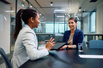 Young businesswoman talks to black female CEO during meeting in office.