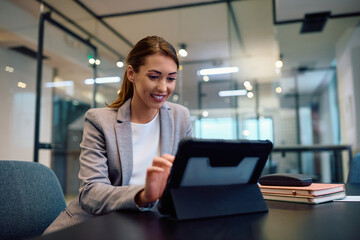 Young happy businesswoman working on digital tablet in office.
