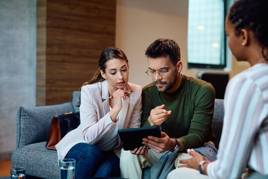 Young Couple Using Digital Tablet During Meeting With Financial Advisor.