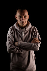 Obraz premium Slim confident man on a black background. Casual clothes. Crossed arms. Psychologist, personal growth coach.