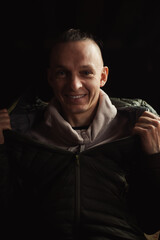 Satisfied smiling middle-aged man on a dark background. A positive person.