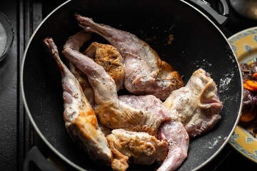 Raw rabbit with spices in a pan. Cooking stewed rabbit.