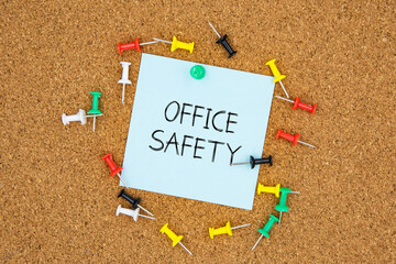 Office safety text on light blue post-it paper pinned on bulletin cork board surrounding by multi...