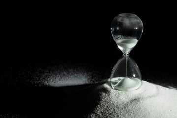 Hourglass add more sand of time on white sand over black background. White hourglass show more time...
