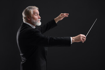 Professional conductor with baton on black background