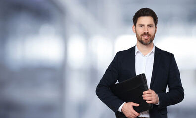 Handsome real estate agent with portfolio in office, space for text