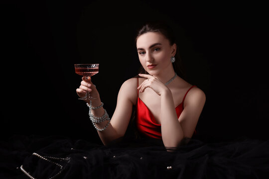 Fashionable photo of attractive young woman with glass of wine on black background