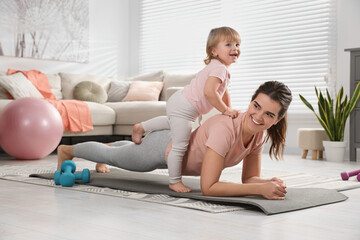 Fototapeta na wymiar Mother doing exercise with her daughter at home