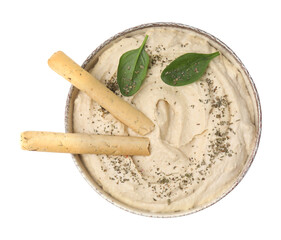 Bowl of delicious hummus with grissini sticks, basil leaves and spices isolated on white, top view